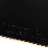 Close-up of a black table tennis paddle surface with embossed text reading 'V-15 Sticky soft' and 'Munich Germany', plus the Victorinox logo, with a light wood edge visible along the bottom.