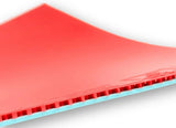 A close-up of a red table tennis rubber with a light blue textured edge showing through the grooves, set against a plain white background.