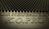 Close-up of a black textured mat with embossed text reading 'DR NEUBAUER K.O.